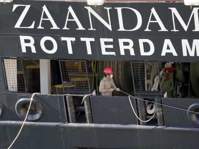 A crew member wearing a protective mask puts out lines as Carnaval's Holland America cruise ship Zaandam arrives at Port Everglades.