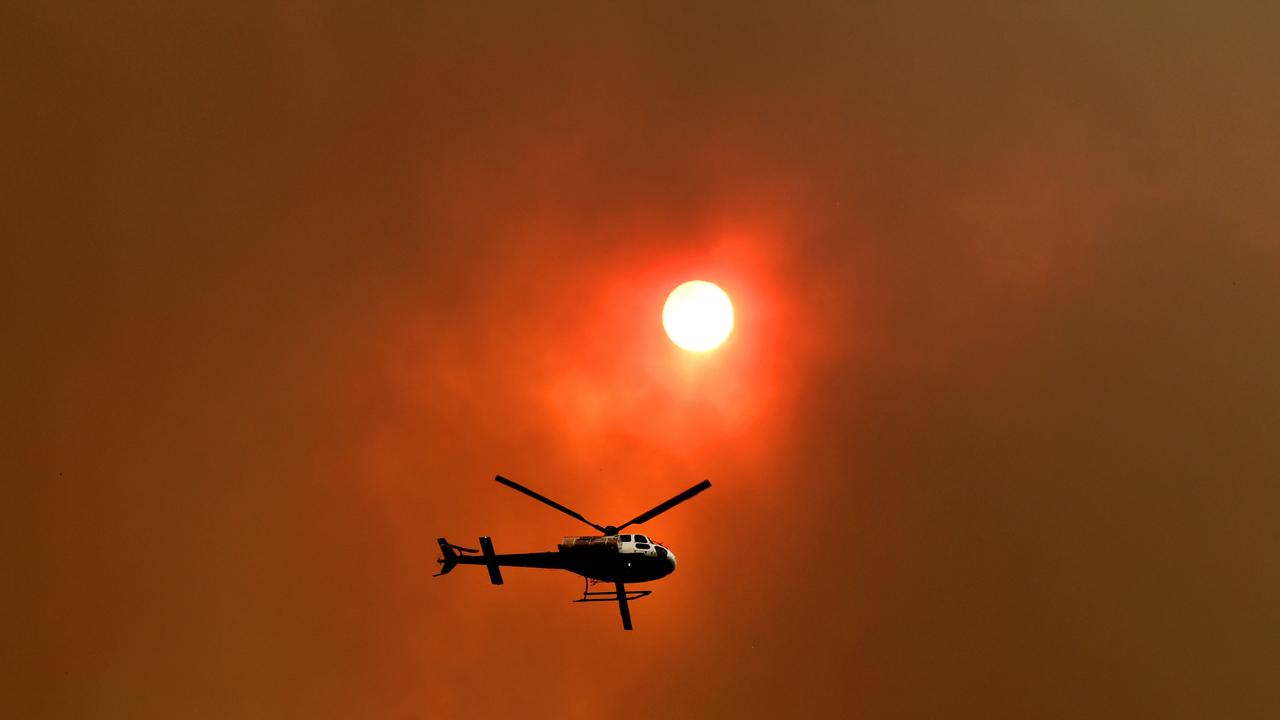 A spotter helicopter flies through thick bushfire smoke at Nana Glen. Picture: AAP