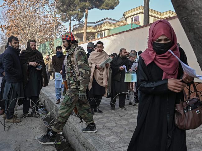 A Taliban fighter walks past people waiting to enter the passport office at a checkpoint in Kabul, after Afghanistan's Taliban authorities said they will resume issuing passports. The passport office had been closed for weeks. Picture: Mohd Rasfan/AFP