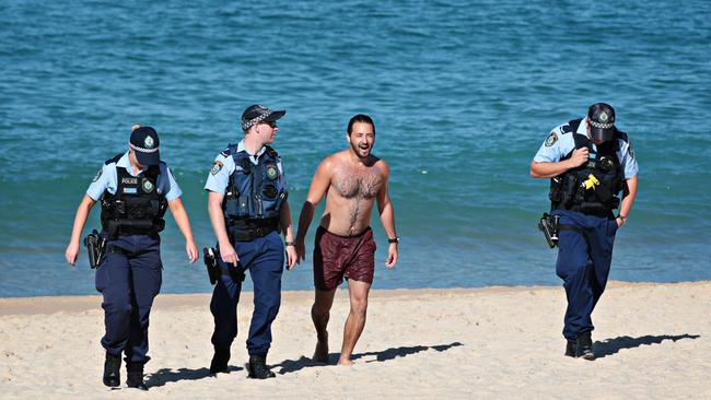 Police escort a man from Coogee beach on April 24 after it was closed due to Covid restrictions. Picture: Adam Yip