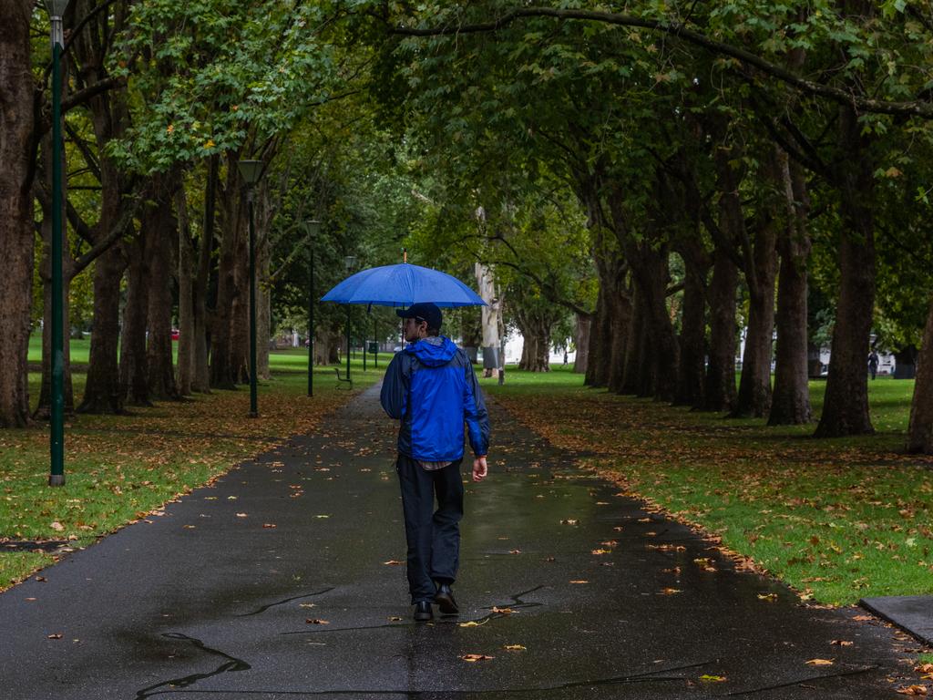 MELBOURNE, AUSTRALIA - APRIL 05: A lone man carrying an umbrella walks through the empty Carlton Gardens on April 05, 2020 in Melbourne, Australia. The Australian government has introduced further restrictions on movement and gatherings in response to the ongoing COVID-19 pandemic. Public gatherings are now limited to two people, while Australians are being urged to stay home unless absolutely necessary. New South Wales and Victoria have also enacted additional lockdown measures to allow police the power to fine people who breach the two-person outdoor gathering limit or leave their homes without a reasonable excuse. Queensland, Western Australia, South Australia, Tasmania and the Northern Territory have all closed their borders to non-essential travellers and international arrivals into Australia are being sent to mandatory quarantine in hotels for 14 days. (Photo by Asanka Ratnayake/Getty Images)