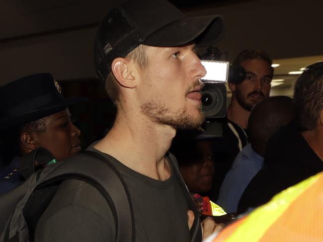 Australia's cricket player Cameron Bancroft, is escorted by police officers to the departure area at OR Tambo International airport in Johannesburg, South Africa. Picture: AP Photo/Themba Hadebe.