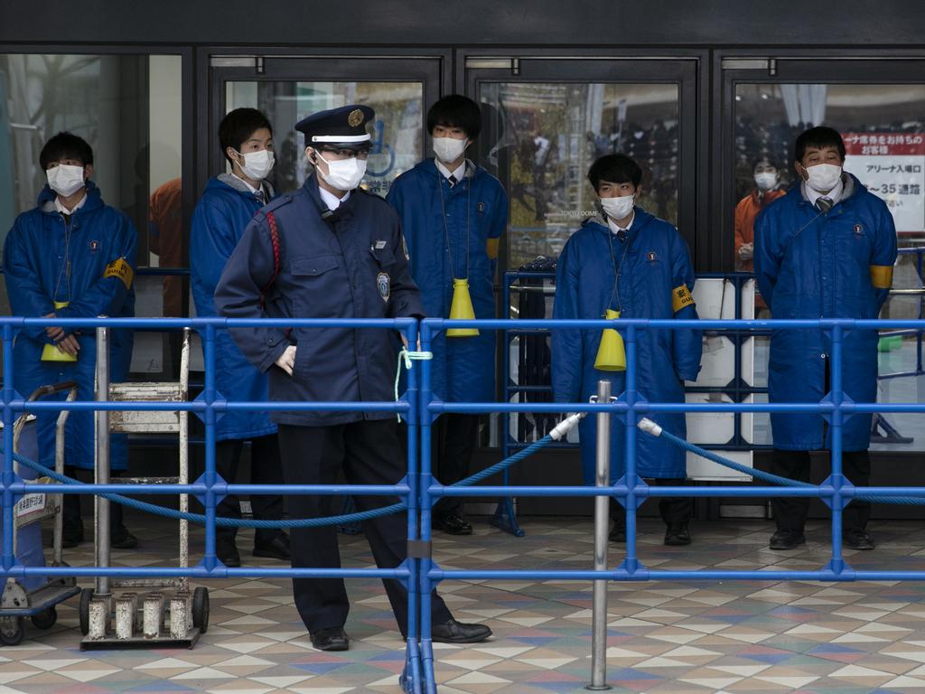 Ushers wear protective face masks before the start of a concert by Japanese girl group Perfume outside Tokyo Dome in Tokyo on Tuesday. Picture: AP Photo/Jae C. Hong.