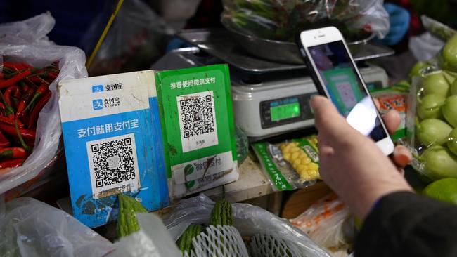 Customers pay at a Beijing vegetable market using an Alipay QR code, left. Picture: AFP