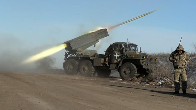 A member of Ukraine's military looks away as a BM-21'Grad' MLRS 122mm rocket launcher fires on the outskirts of Soledar on January 11, 2023. Picture: Arman Soldin / AFP.