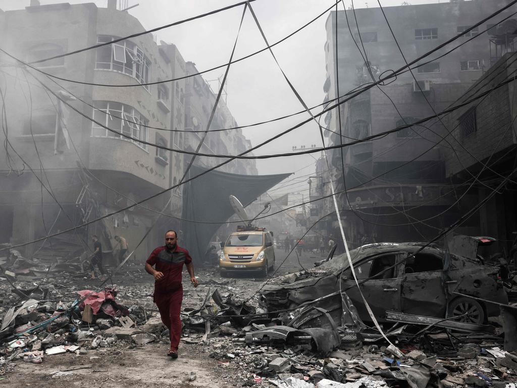 A Palestinian runs amidst the debris after an Israeli airstrike on buildings in the refugee camp of Jabalia in the Gaza Strip. Picture: AFP