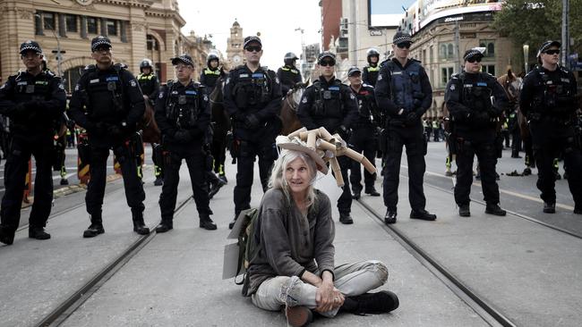 A woman sits down in front of a police line in Flinders St. Picture: Darrian Traynor/Getty Images