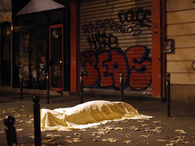 A victim under a blanket lays dead outside the Bataclan theatre.. (AP Photo/Jerome Delay)