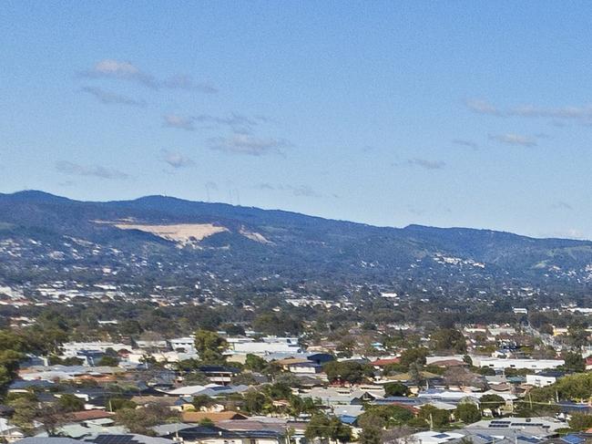 Aerial view looking down on new, modern Adelaide housing development with mixed house & architectural styles: single level houses, townhouses, construction site, green space, established suburb & city in background. Picture: iStock/BeyondImages