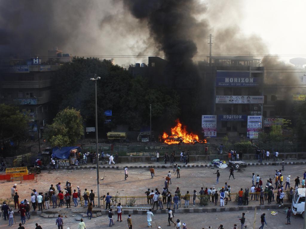 People watch car burn during clashes between hundreds of supporters and opponents of a new citizenship law in New Delhi, India. Picture: AP