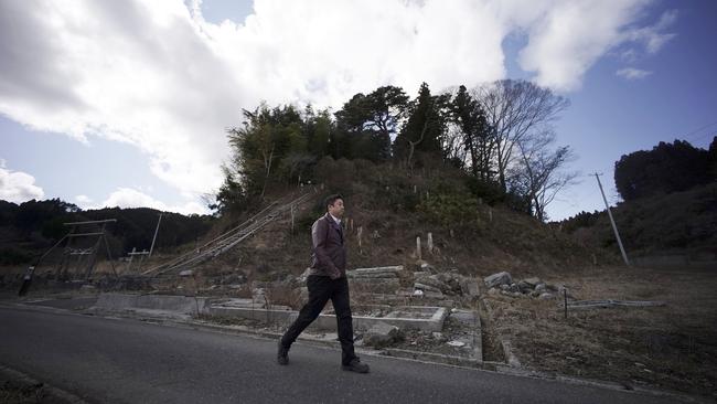 Michihiro Kono walks by a hill where his company's employees ran up to a shrine for safety when the 2011 tsunami hit Rikuzentakata.