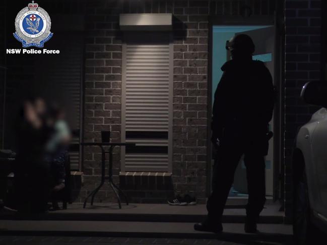 One of the women arrested is holding a baby as a police officer watches on nearby. Picture: NSW Police