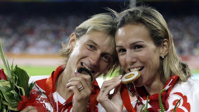 Russia's gold medal winner Gulnara Galkina-Samitova, left, and bronze medal winner Ekaterina Volkova bite their medals after the women's 3000-meter steeplechase at the Beijing 2008 Olympics.