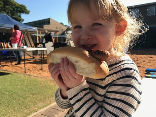 Elizabeth Fanning, 3, tucks into her full mark sausage sanga.