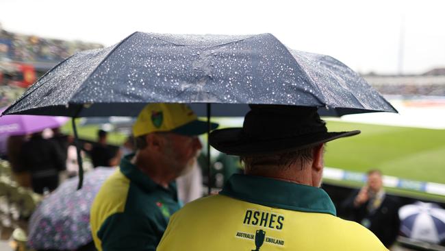 Australian fans shelter from the rain under on day three. Picture: Getty