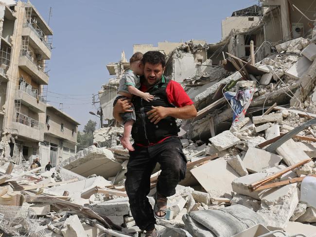 A Syrian man carries a baby after removing him from the rubble of a destroyed building following a reported air strike in the Qatarji neighbourhood of the northern city of Aleppo. Picture: AFP.
