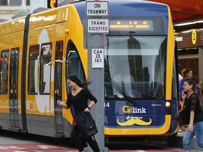 Schoolies celebrations at Surfers Paradise on the Gold Coast. Pedestrians run across in front of a tram about to leave the station. Picture Glenn Hampson