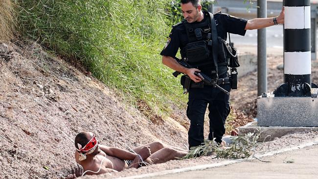 A member of the Israeli security forces stands next to a blindfolded Palestinian prisoner near Ashkelon on October 8. Picture: AFP