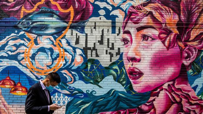 A man wearing a protective face mask walks past a mural in Hong Kong on February 24.