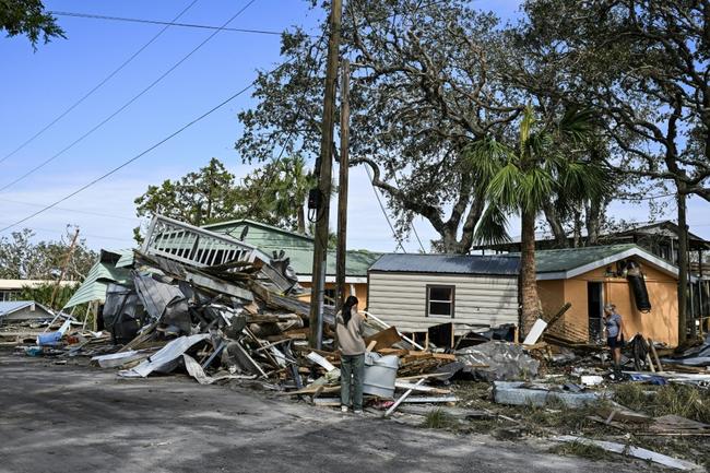 Terry Maulden (R) and Sotgerel Tegshee (L) inspect damages of their damaged house after Hurricane Helene made landfall in Horseshoe Beach, Florids