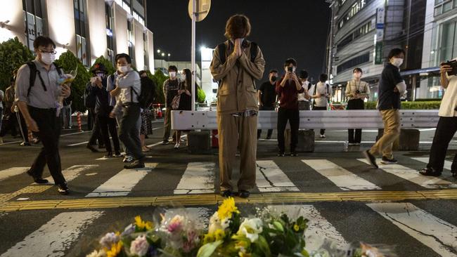 People pray at the site where Mr Abe was shot.