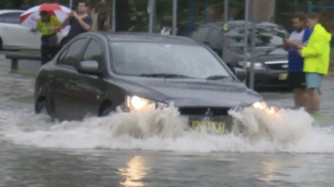 A car attempts to drove through floodwaters. Credit: TNV