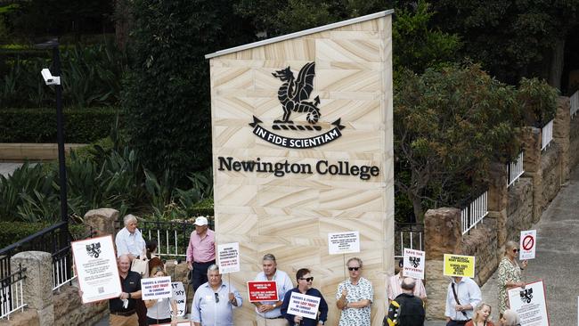 Pictured in Stanmore outside Newington College as boys arrive for their first day of the new school year, are parents with placards during a silent protest against the proposed switch to Newington College becoming a co-ed school. Picture: Richard Dobson