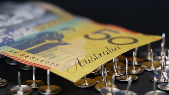 close up extreme shallow depth of field macro shot of australian fifty dollar note supported on sharp thumb tacks or drawing pins. Finance business economy concept. Debt trap generic money