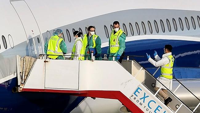 Officials prepare to board before passengers disembark a charter flight at Melbourne's Airport on April 12. Picture: AFP