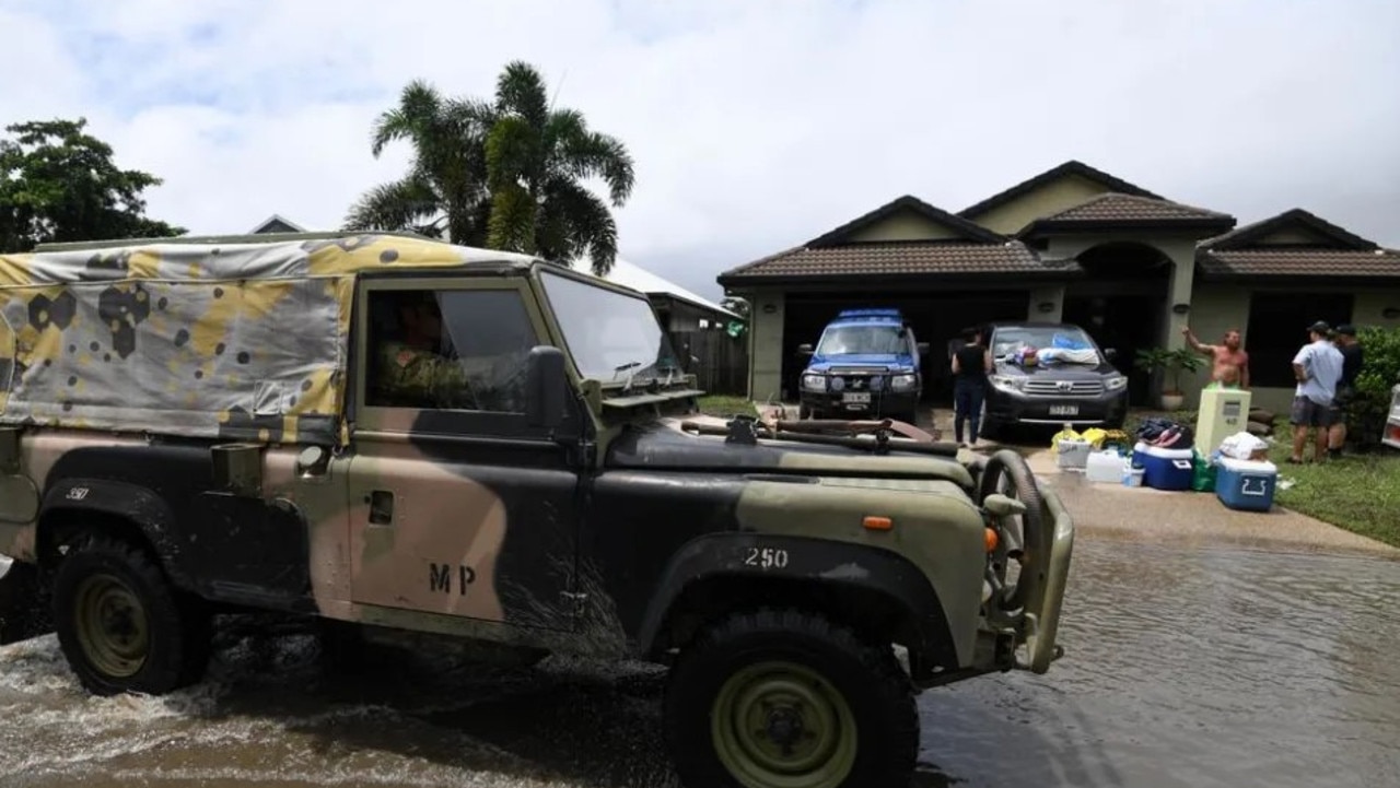 An army vehicle drives past houses affected by floods in Townsville, in 201 after days of torrential rain. Picture: AAP Image/Dan Peled.