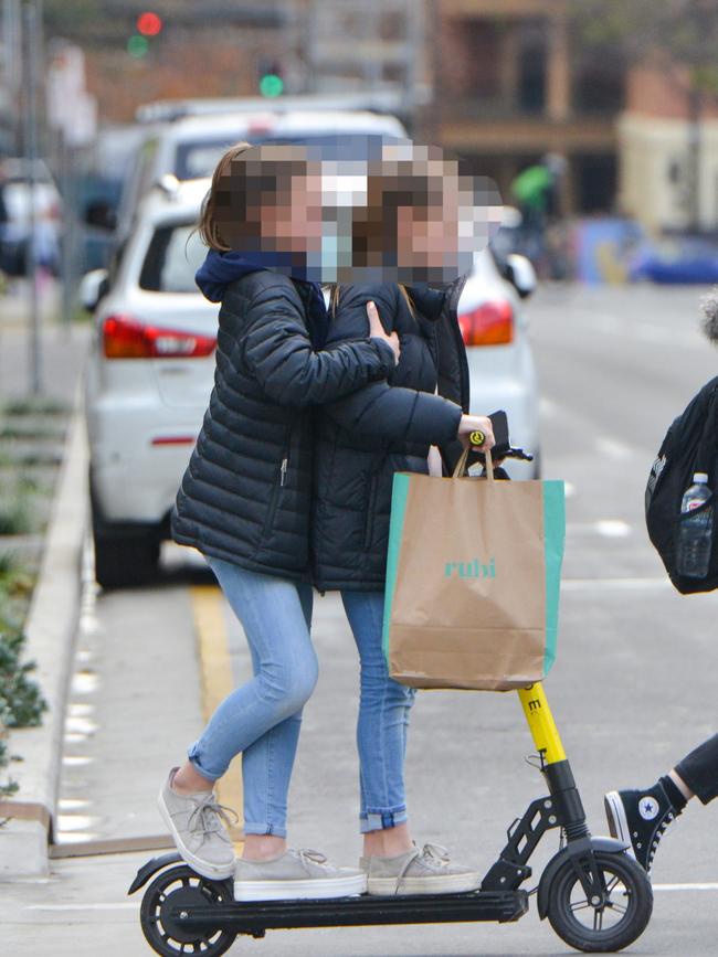 Two young girls without a helmet riding tandem on a scooter along Grenfell St. Picture: Brenton Edwards