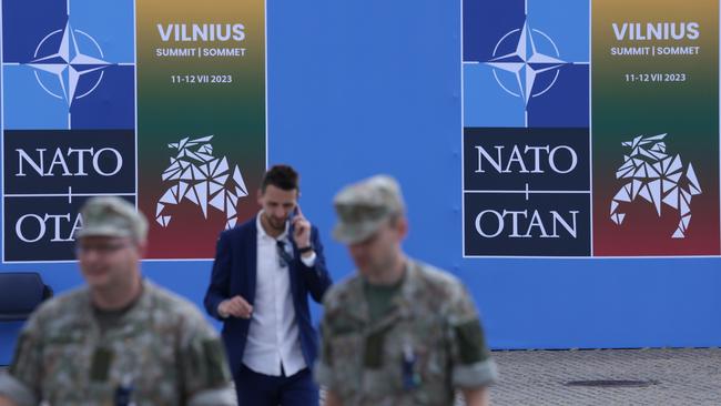 Soldiers walk past a poster at the NATO summit venue in Vilnius, Lithuania.