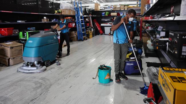 . Workers clean up smoke damage in the adjoining factory, Sydney Tools. Picture: Glenn Hampson