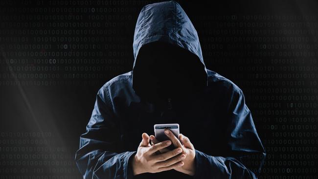 Internet crime concept, Hooded hacker using smartphone in dark room istock image