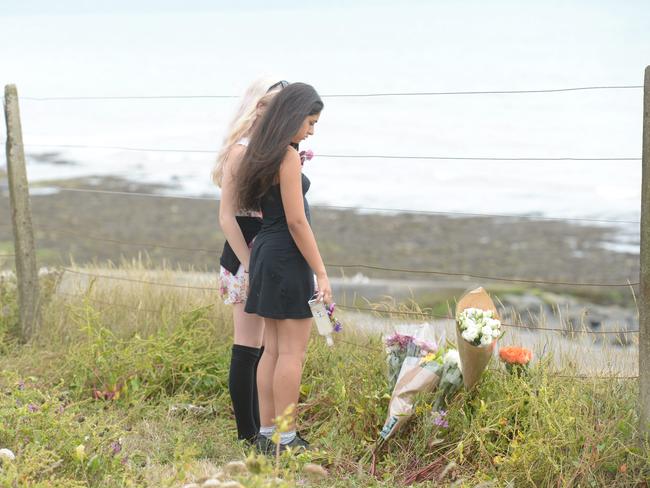 Grieving ... Teenagers lay floral tributes at the edge of the cliff.