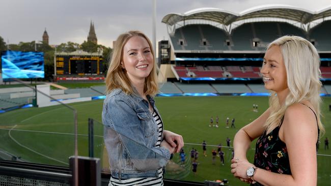 Adelaide Oval staff members Sarah Vincent and Elise Partington in the western stand, while the video plays on screens below. Picture: Naomi Jellicoe