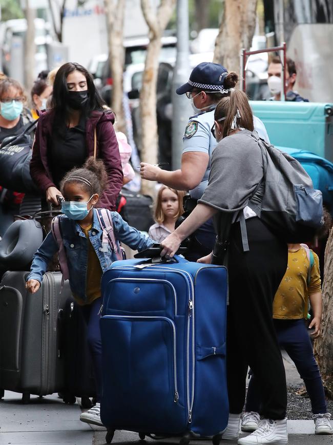 Police escort travellers into a Sydney hotel. Picture: David Swift.