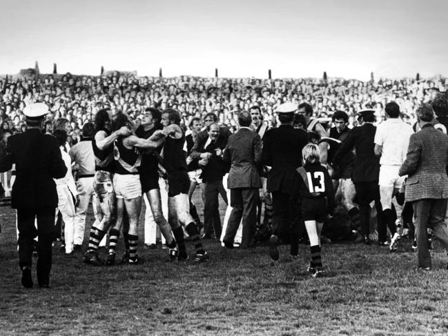 Players, coaches, fans and officials get involved in the infamous 1974 Richmond and Essendon fracas at Windy Hill. Richmond team manager Graeme Richmond (middle, in suit and tie) is pulled away. Tiger Wayne Walsh is pictured behind Richmond's right shoulder, teammate Bryan Wood is far left, while Bomber Laurie Moloney (wearing No. 34) is far right. Identifiable players in the scuffle are, from left, Ian Stewart, Paul Sproule (wearing No. 6) and Ken Fletcher.