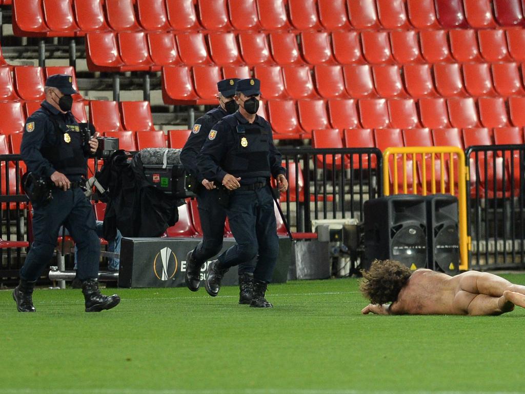 Security forces walk towards a streaker who invaded the pitch during the UEFA Europa League football match between Granada FC and Manchester United.