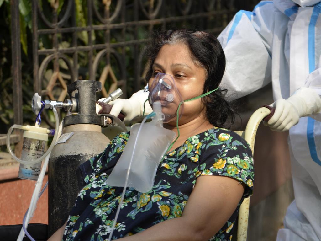 A COVID-19 patient on a wheelchair goes for a medical test inside a government hospital in Kolkata.