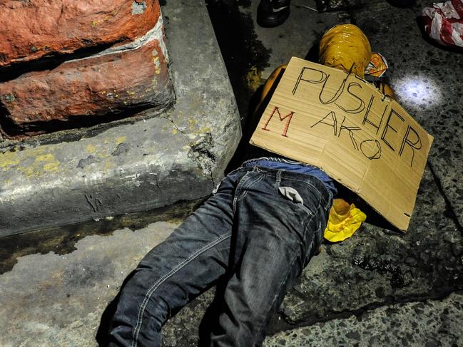MANILA, PHILIPPINES - JULY 08: (EDITORS NOTE: Image contains graphic content.) An alleged drug dealer and victim of a summary execution with his head wrapped in tape is examined by police on July 8, 2016 in Manila, Philippines. Philippine President Rodrigo Duterte declared a war on crime and drugs after winning the presidential elections on May 9, 2016. President Duterte has recently been living up to his nickname, 'The Punisher', as Philippine police have been conducting night time drug raids on almost a daily basis. With reports of at least 300 drug related deaths since the start of July, Human rights groups and the Catholic church have objected to the use of brutal force by the Police. (Photo by Dondi Tawatao/Getty Images)
