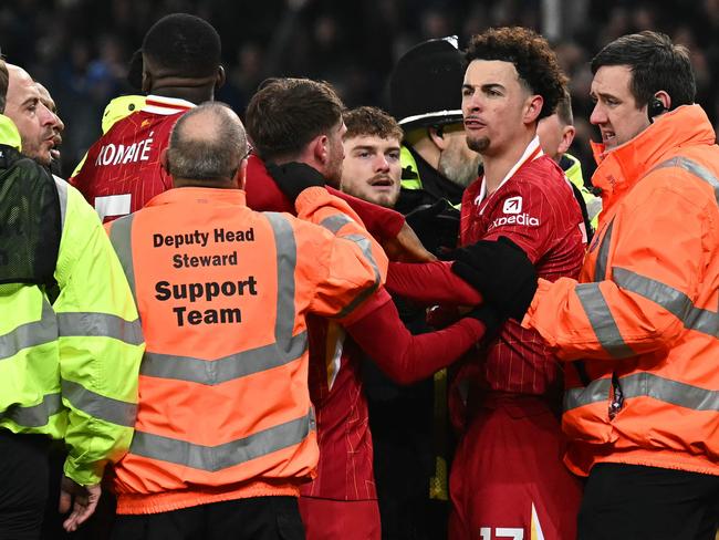 Liverpool's English midfielder #17 Curtis Jones is held back by stewards as he remonstrates with Everton players after the English Premier League football match between Everton and Liverpool at Goodison Park in Liverpool, north west England on February 12, 2025. The match ended in a draw at 2-2. (Photo by Paul ELLIS / AFP) / RESTRICTED TO EDITORIAL USE. No use with unauthorized audio, video, data, fixture lists, club/league logos or 'live' services. Online in-match use limited to 120 images. An additional 40 images may be used in extra time. No video emulation. Social media in-match use limited to 120 images. An additional 40 images may be used in extra time. No use in betting publications, games or single club/league/player publications. /