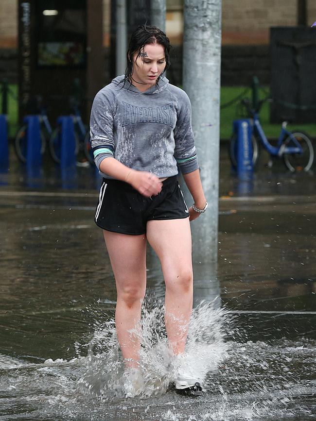 Pedestrians walk through the water along Flinders Street. Picture: Ian Currie