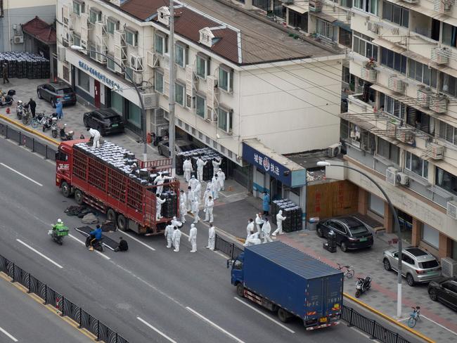 Workers wearing personal protective equipment transfer daily food supplies and necessities for local residents during the Covid-19 lockdown in Shanghai. Picture: AFP/China OUT