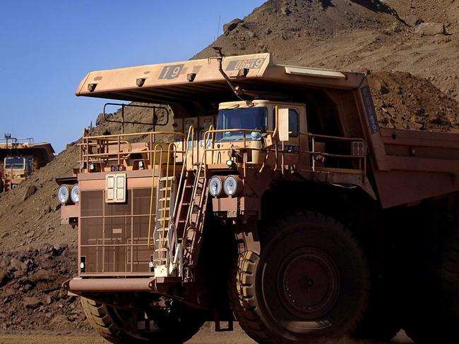 Heavy earth moving trucks at the Tom Price iron ore mine, operated by Rio Tinto Group, are lit up by the afternoon sun in Pilbara, north Western Australia on Wednesday, July 26, 2006. BHP Billiton Ltd., the world's largest mining company, is losing the support of investors and steelmakers for its proposed $128 billion takeover of Rio Tinto Group. Photographer: Jack Atley/Bloomberg News