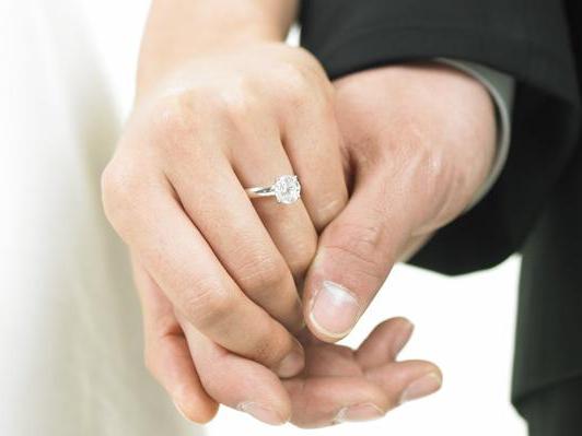 a bride wearing a wedding ring and a bridegroom holding her hands