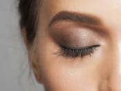 Close-up istock image of a woman's eye closed with eyelash extensions, eyeshadow, and filled in eyebrows