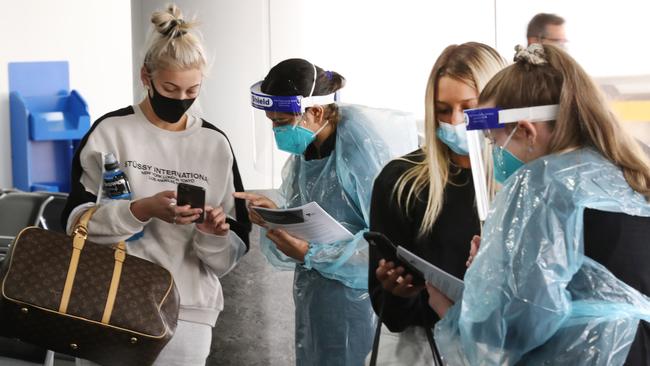 Mia Giuliani and Matilda Bredon are checked by COVID staff on arrival at Melbourne Airport. Picture: David Crosling