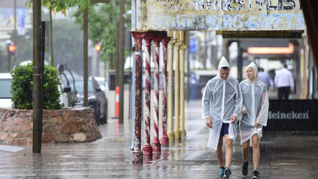 Pedro Jose Menendez and Krystle Jorja shelter from the rain while they walk down Flinders Street in Townsville. Picture: Wesley Monts