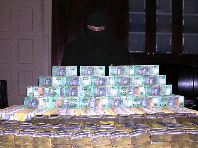 A man in a balaclava said to be surfer Shayne Hatfield poses with a huge pile of cash in a 2005 copy photo. The photo was found when police from Operation Mocha raided his house and arrested him. Hatfield was allegedly part of a cocaine trafficking syndicate.